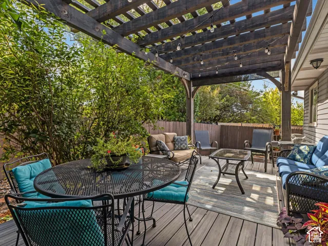 Expansive outdoor deck featuring a wooden pergola and string lighting