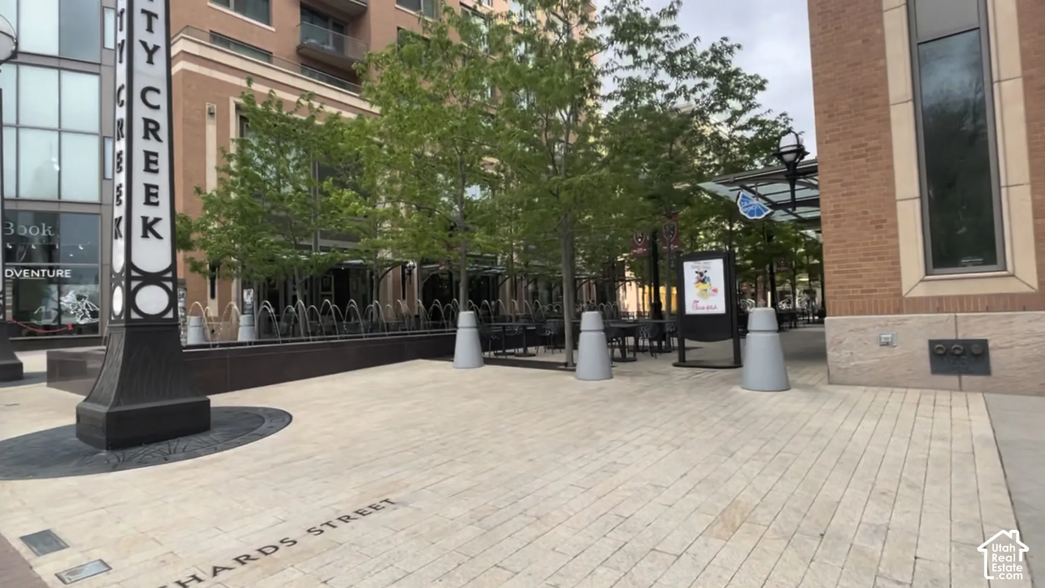 Paver stone walking surface with integrated street name, surrounded by established trees and a decorative water feature