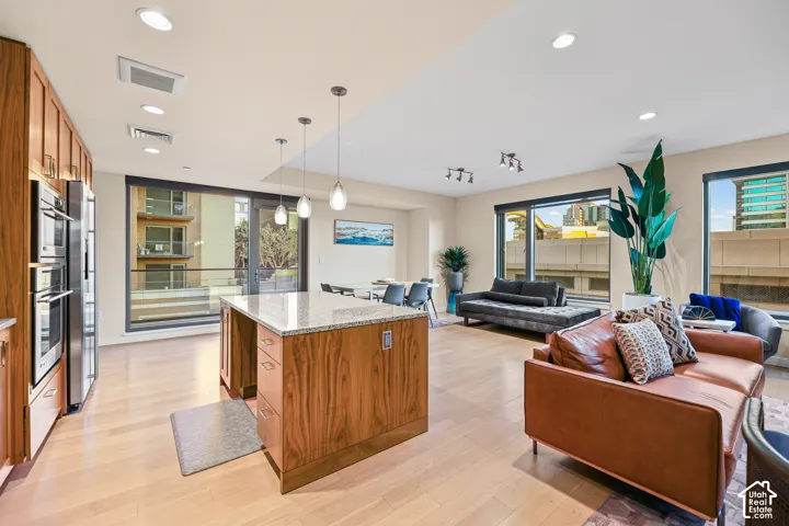 Open-concept living space with light wood-finish flooring, recessed lighting, and large windows