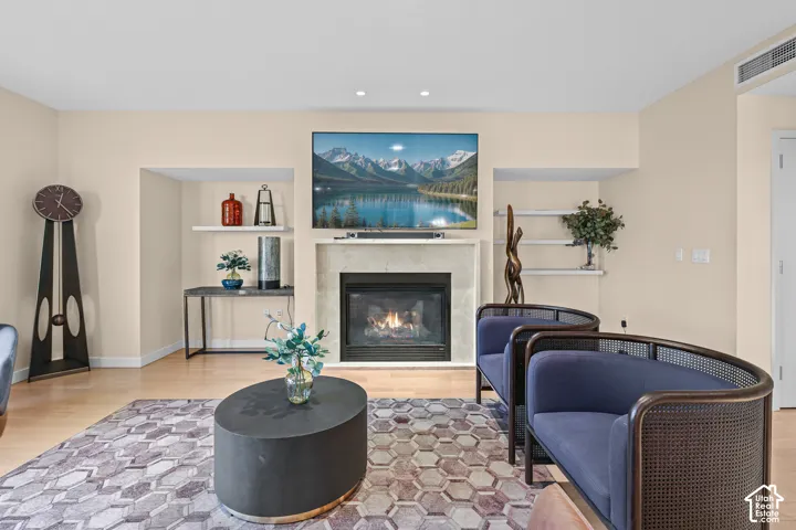 Fireplace with stone surround and mantle, built-in shelving, and light wood-finish flooring