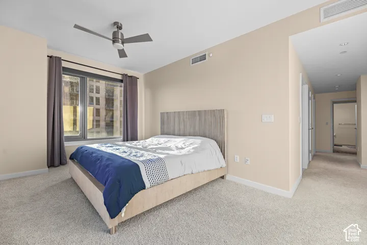 Wall-to-wall carpeting, ceiling fan, and large window with dark window treatments