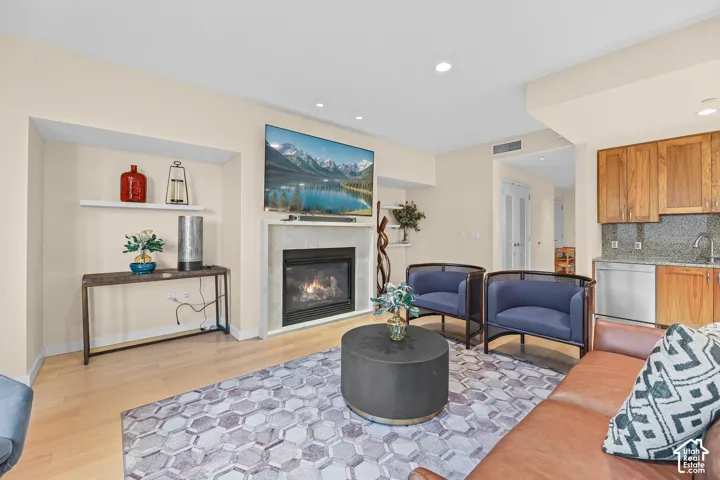 Recessed fireplace with a stone surround, built-in shelving, wood-finish flooring, recessed lighting, and kitchen cabinetry