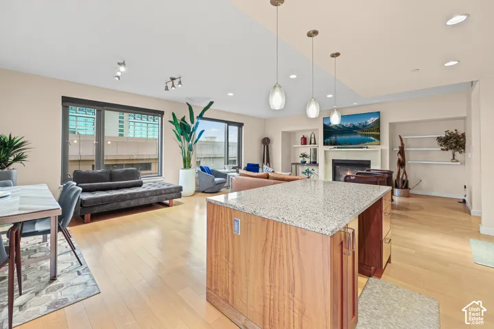 Open-concept living space with light wood-finish flooring, recessed lighting, and large windows