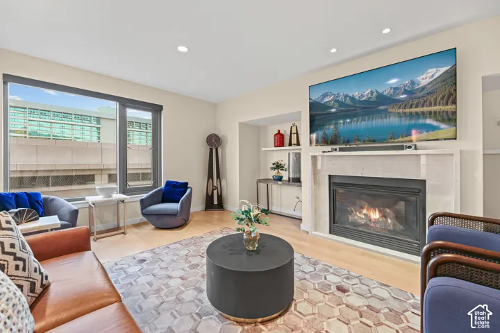 Light-toned wood-finish flooring, recessed lighting, and a modern fireplace with a light-colored surround