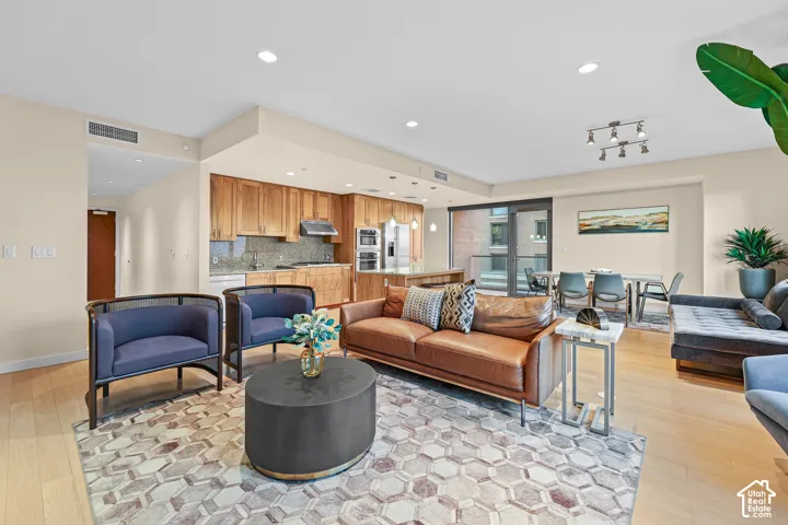 Open-concept living space featuring wood-finish flooring, recessed lighting, and a modern kitchen with wood cabinetry