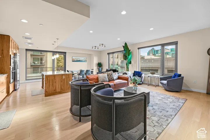 Open-concept living space featuring wood-finish flooring, recessed lighting, and large windows