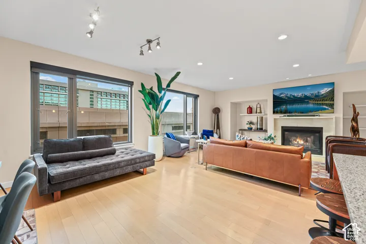 Hardwood flooring, recessed lighting, and large windows with roller shades