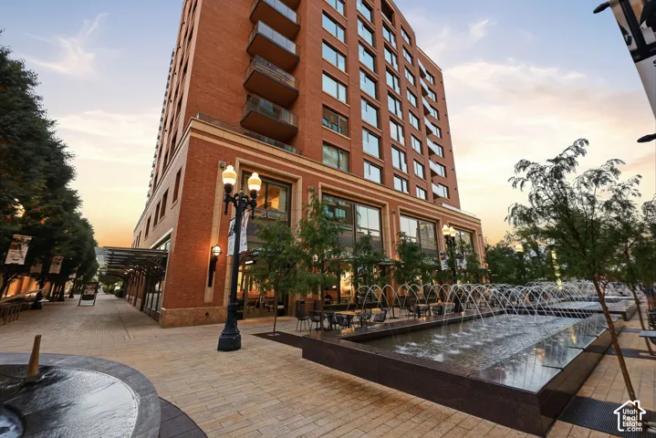 Brick exterior with balconies, ground-floor commercial spaces, and an outdoor water feature