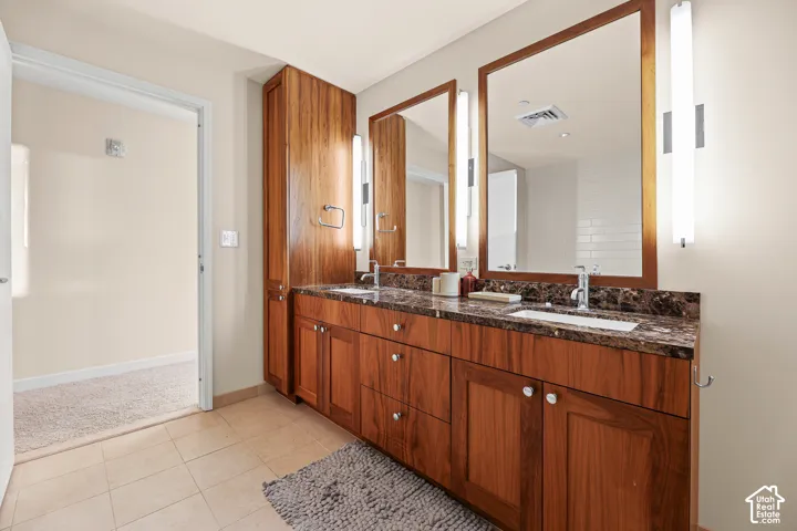 Dual vanity with wood-finish cabinetry, integrated sinks, and polished chrome fixtures