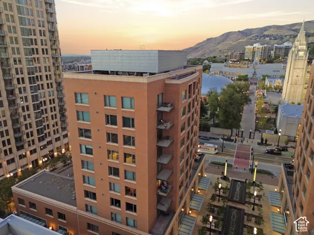 Brick facade building with balconies, surrounded by urban cityscape, and distant mountains