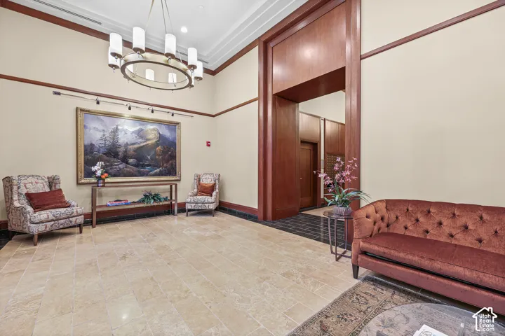 Spacious foyer featuring light-toned tile flooring, rich wood-paneled walls, and a recessed ceiling with a large circular chandelier