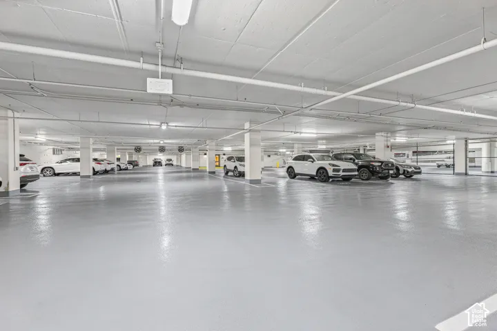 Spacious subterranean parking garage with a light gray epoxy floor coating, white support columns, and overhead fluorescent lighting