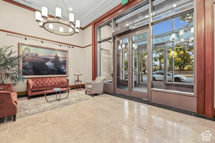 Polished tile flooring, a large circular chandelier, and extensive full-height windows frame the entrance