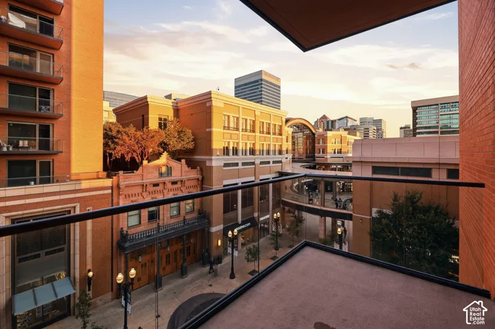 Balcony featuring glass panel railing and urban architecture