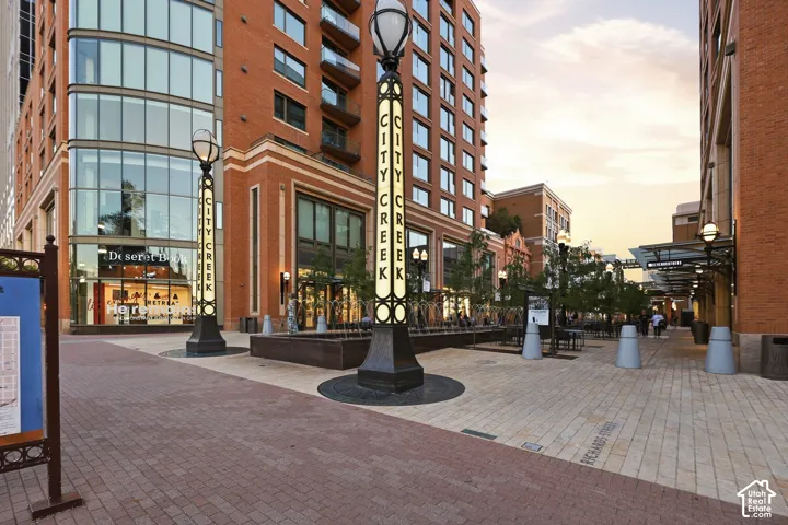 Brick facade with expansive window lines, integrated street lighting, and a paved walkway