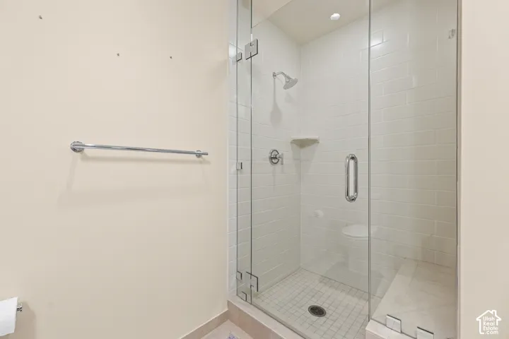 Glass-enclosed shower with white subway tile, a built-in shower bench, and a square-patterned tile floor
