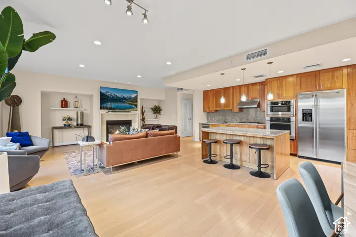 Open-concept living space featuring wood-finish flooring, recessed lighting, and a fireplace with a mantel