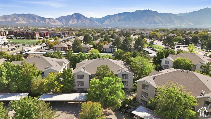 Mountain backdrop, multiple residential buildings, covered parking structures, mature trees, and paved roadways