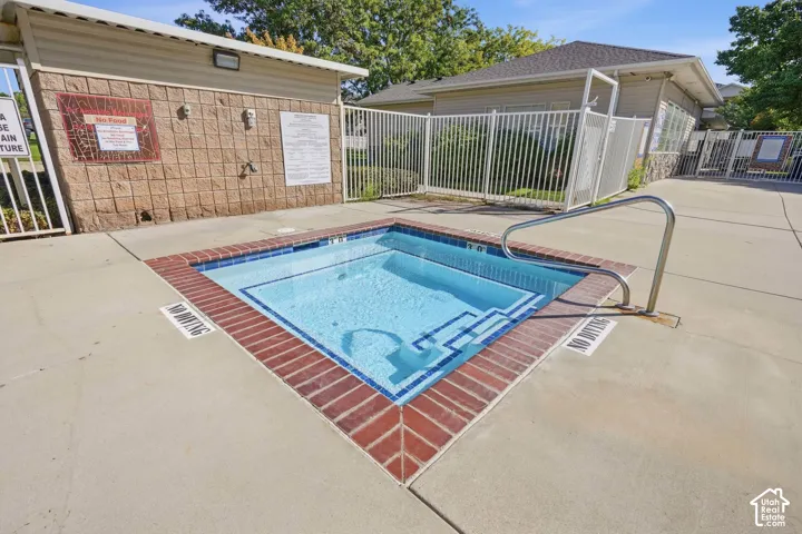 In-ground spa with brick coping and a stainless steel grab bar, surrounded by a concrete deck