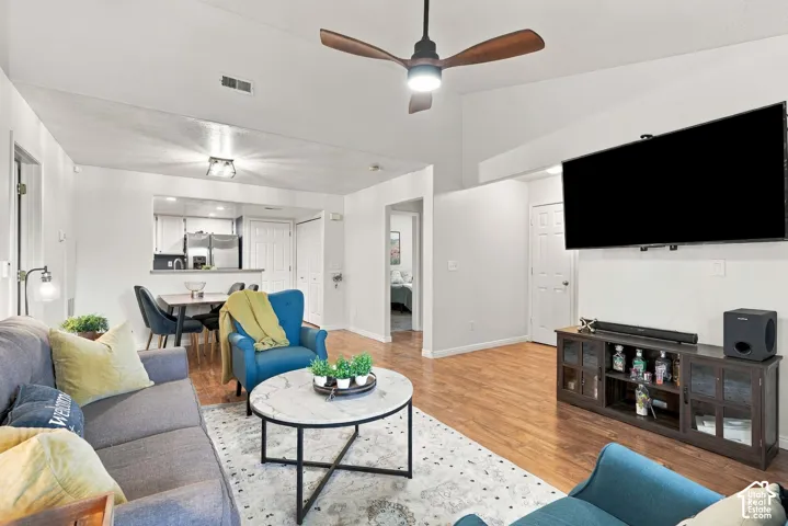Vaulted ceilings with a ceiling fan, recessed lighting, wood-finish flooring, and a pass-through opening to the kitchen