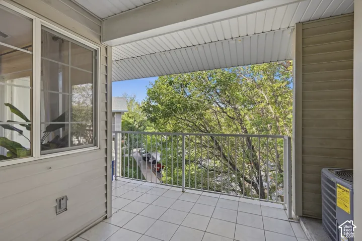 Balcony featuring a tiled floor, metal railing, and a window with grid detailing