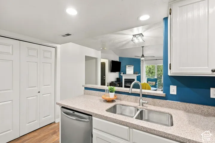Kitchen featuring a stainless steel double basin sink with a gooseneck faucet, light-toned countertop, and white cabinetry