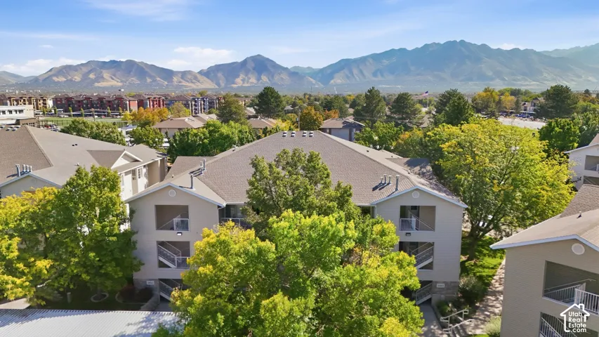 Multi-story residential buildings with balconies, surrounded by mature trees and mountain scenery