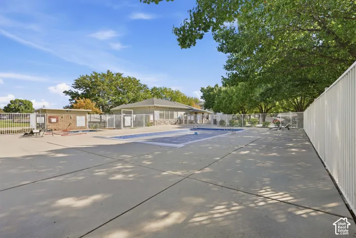 Outdoor swimming pool with a covered surface, surrounded by concrete decking and a metal fence