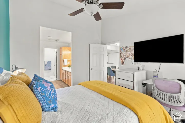 Ceiling fan with light fixture, light wood-finish vanity with countertop, wood-finish cabinetry, built-in shelving, white door