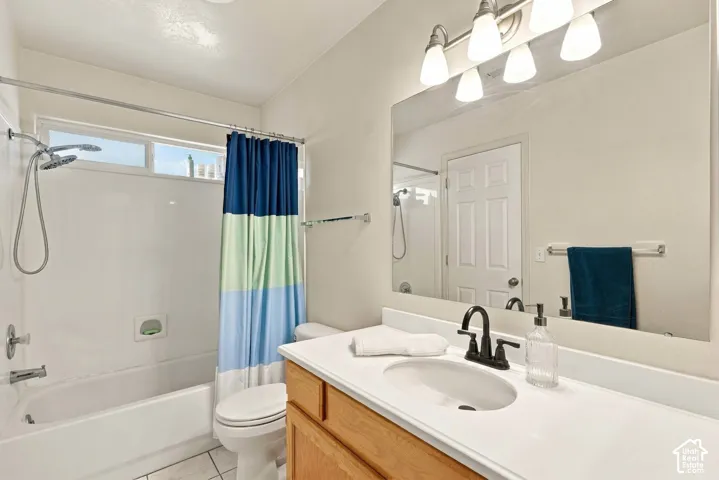Bathroom featuring a full-width vanity mirror, a single vanity with a white countertop and integrated sink, a dark-finish faucet, and a shower-over-tub combination with a transom window