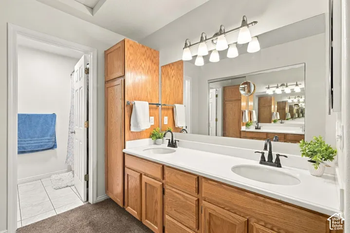 Double vanity with light wood-finish cabinetry, white countertops, and matte black dual-handle faucets
