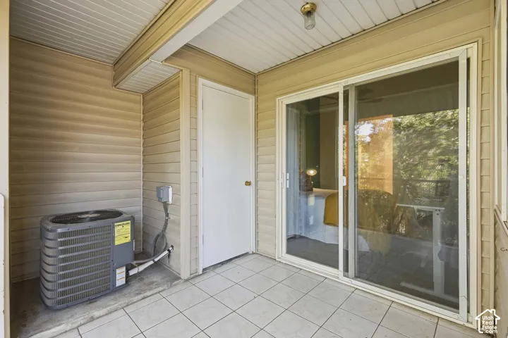 Covered patio featuring tiled flooring, vinyl siding, a sliding glass door, and an exterior door