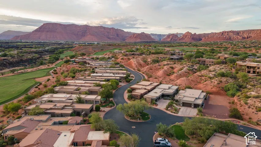 Residential properties with arid landscaping, winding paved roads, and a prominent mountain backdrop