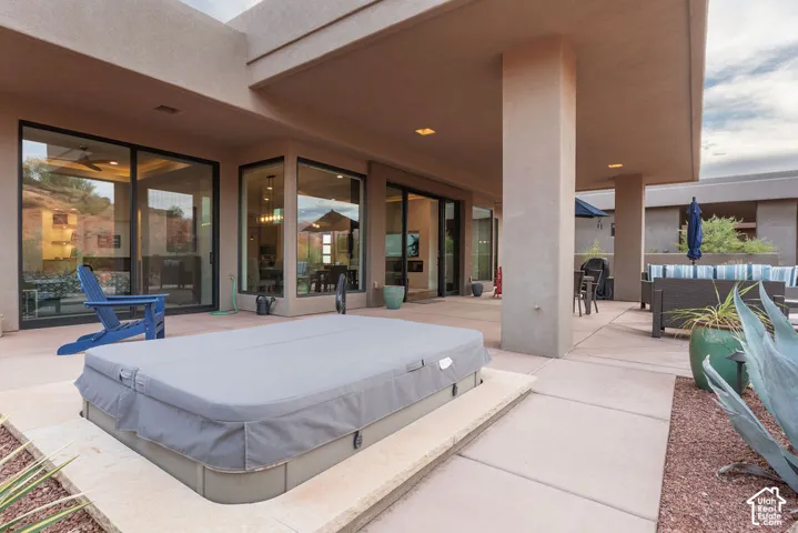 Expansive outdoor patio with concrete paving, a built-in spa, and a covered section for shaded outdoor living