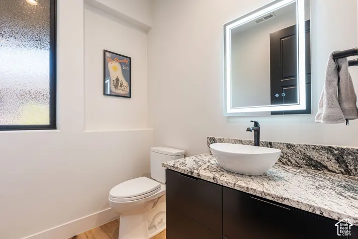 Modern vanity with a vessel sink, dark wood-finish cabinetry, and a granite-pattern countertop