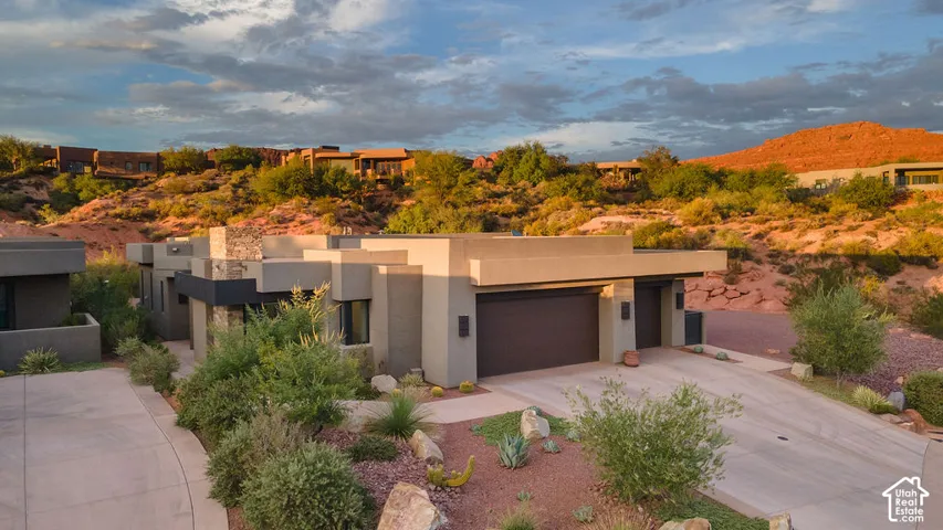 Modern architectural design with a flat roofline, neutral-toned stucco exterior, and integrated two-car garage