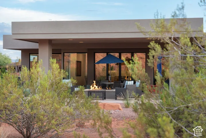 Expansive covered patio with multiple sliding glass doors, a built-in fire feature, and a paved outdoor surface