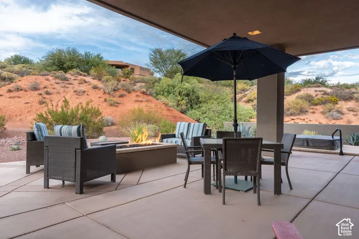 Expansive concrete patio with a built-in fire pit, covered outdoor living space, and a hot tub