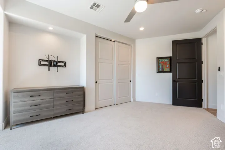 Recessed wall niche with integrated lighting, a ceiling fan with integrated lighting, white paneled double doors, black paneled door, and neutral carpet flooring