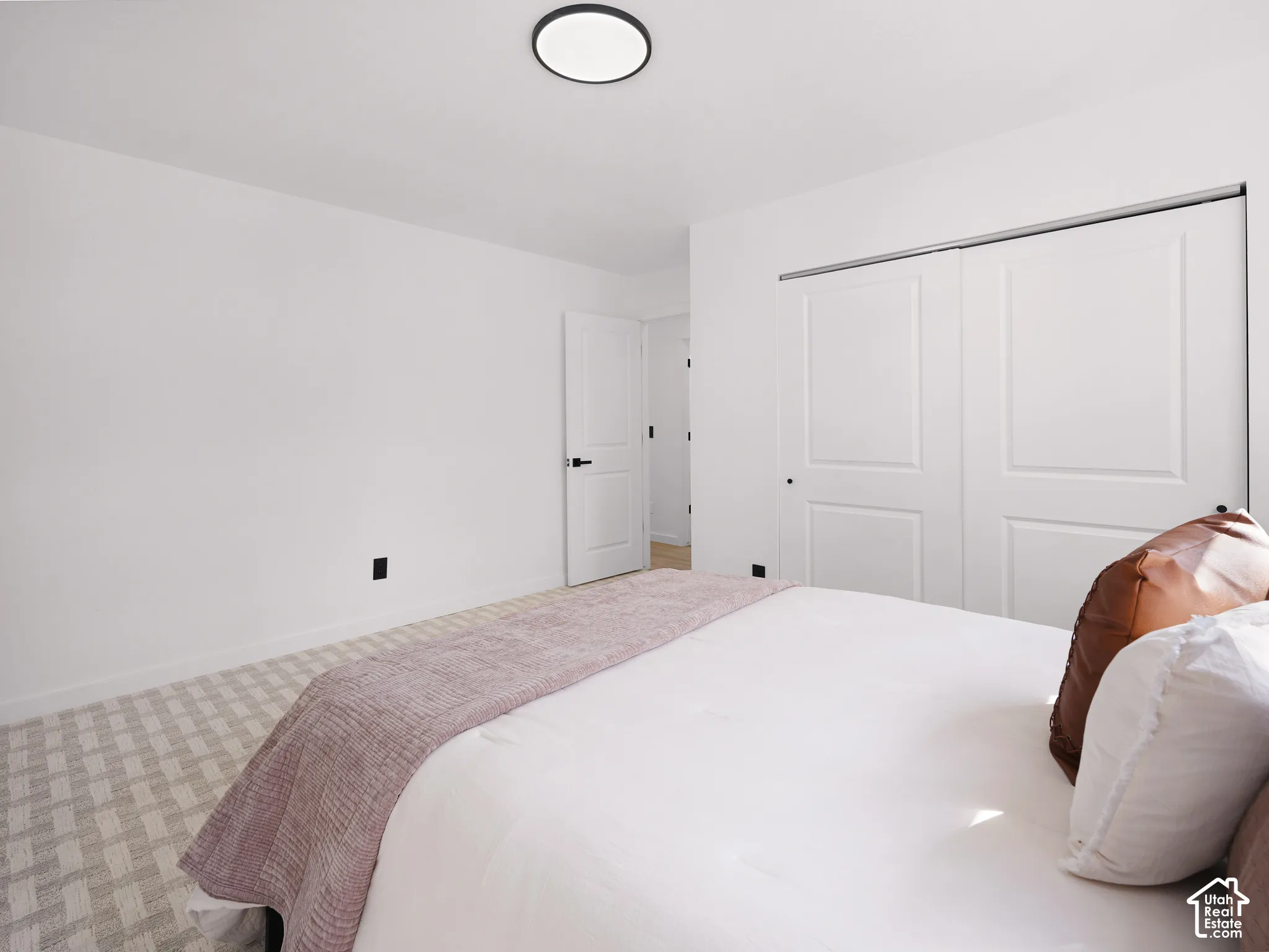 Recessed ceiling light fixture, white walls, built-in closet with sliding panel doors, and a paneled interior door with dark hardware
