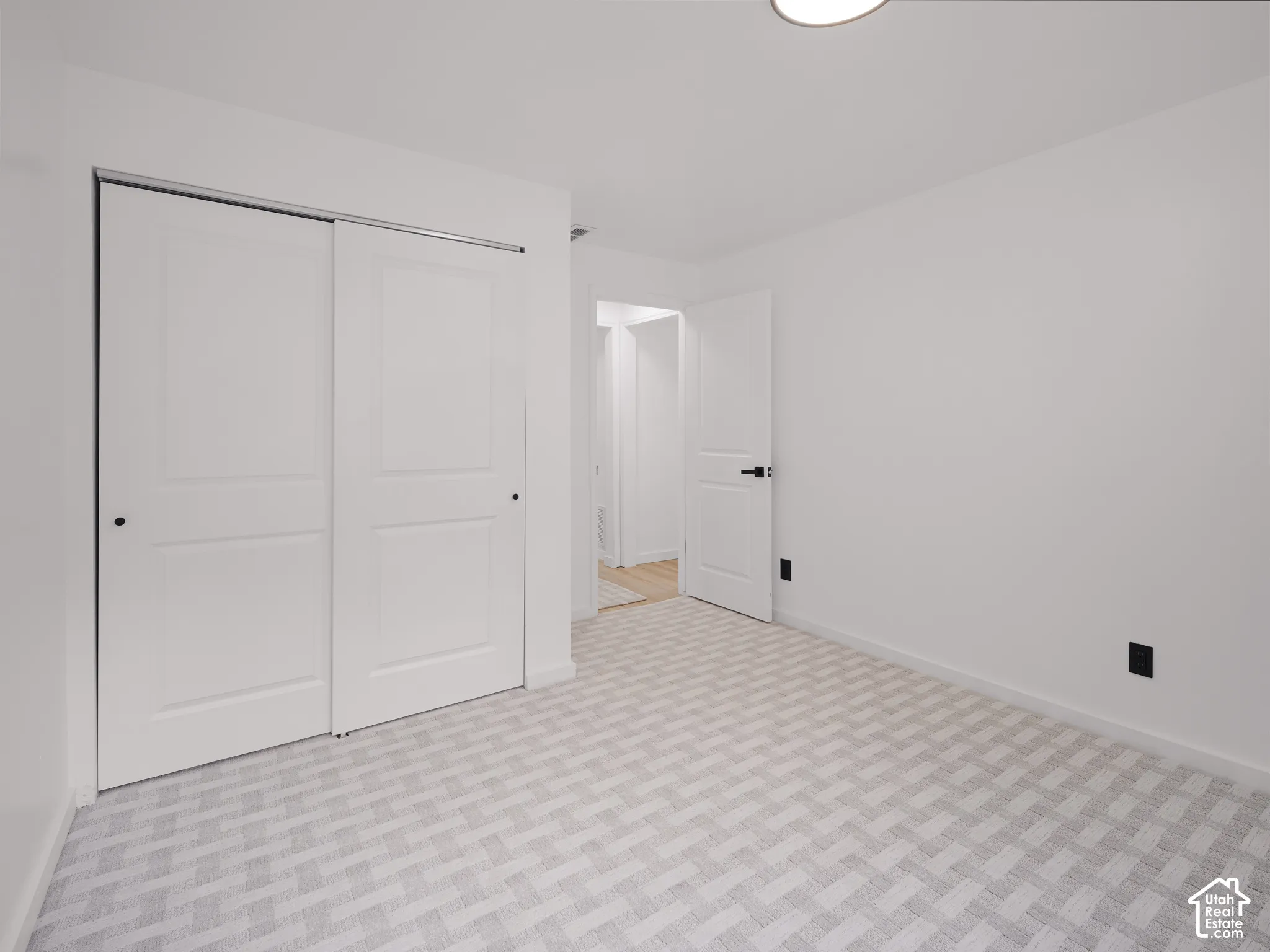 Room featuring neutral color palette, patterned carpeting, white walls, and a built-in closet with sliding doors