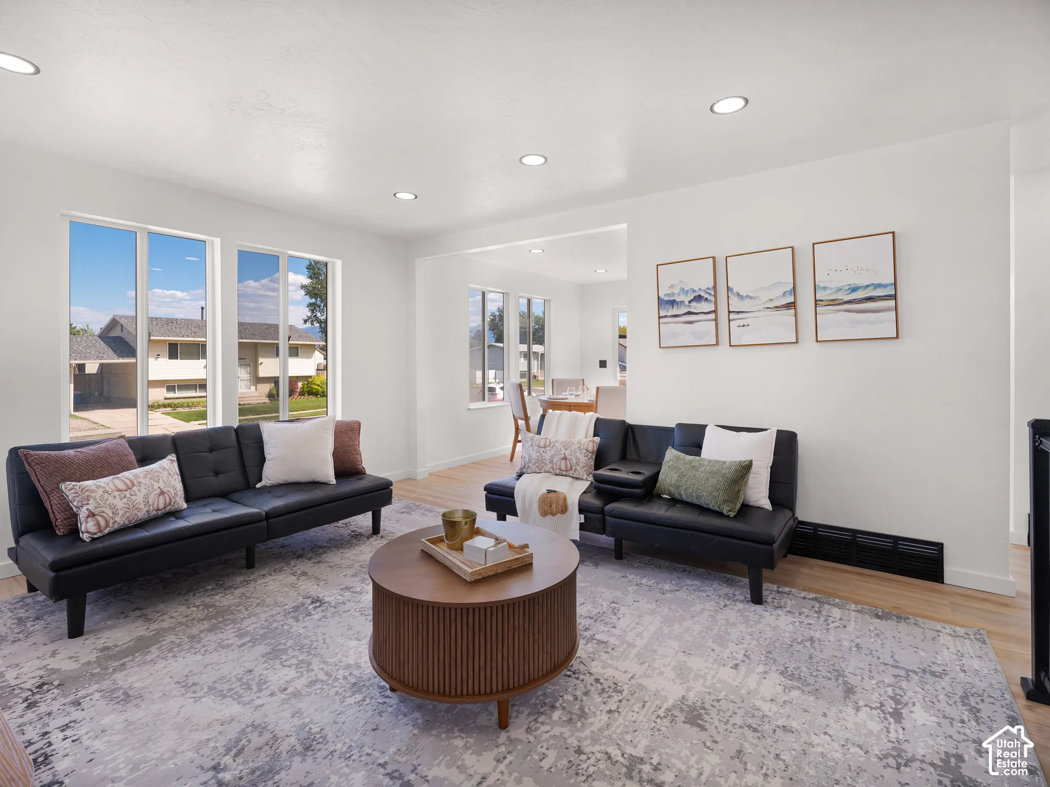 Recessed ceiling lighting illuminates the living area, featuring light wood-finish flooring