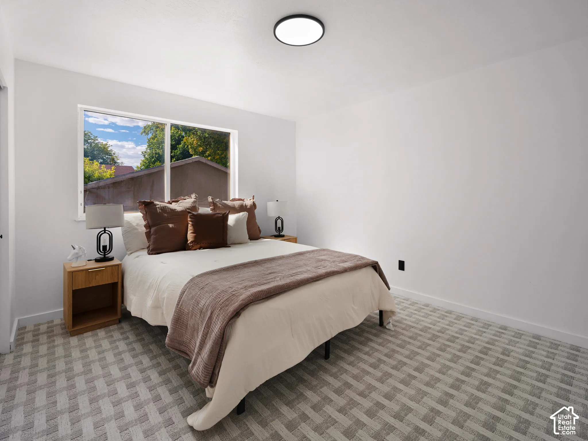 White walls, patterned carpet flooring, and a large window