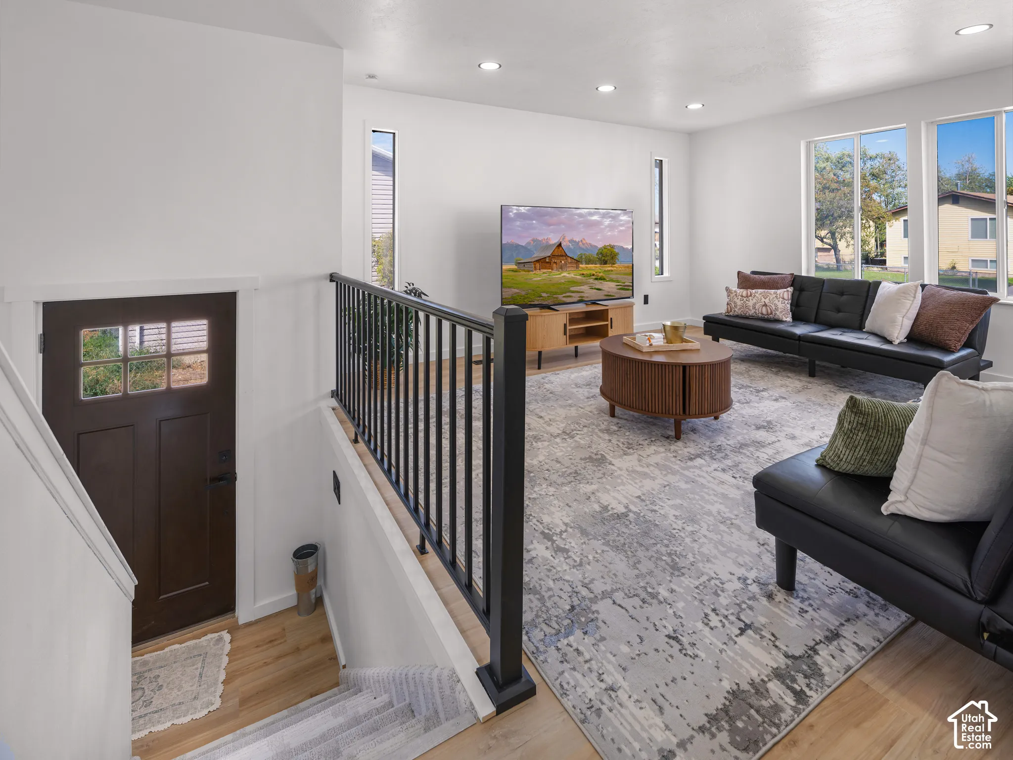 Open-concept living area featuring wood-finish flooring, recessed lighting, and large windows