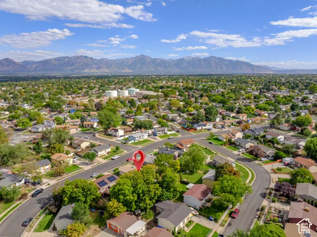 Expansive residential area with numerous detached properties, abundant mature trees, and visible mountainous backdrop