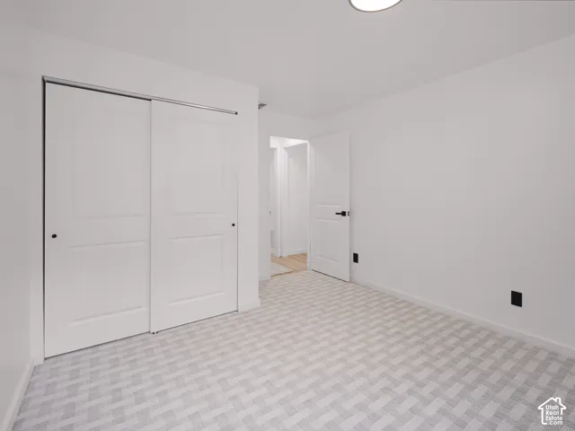 Room featuring neutral color palette, patterned carpeting, white walls, and a built-in closet with sliding doors