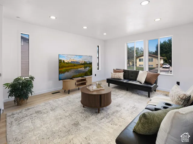 Recessed ceiling lighting, wood-finish flooring, multiple windows, and white wall finishes create a bright interior