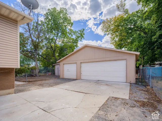 Detached three-car garage with overhead doors, an adjacent shed, and a concrete driveway