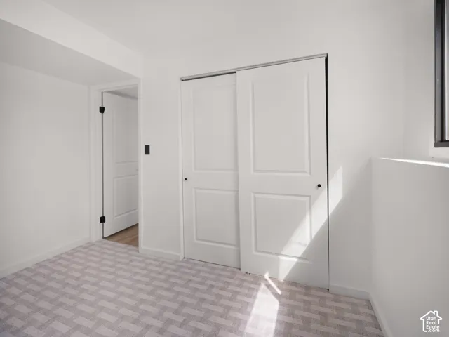 Neutral tone wall paint, light-colored patterned carpet, white sliding closet doors, and a black-framed window