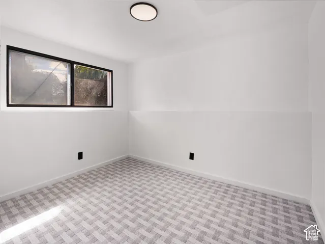 Recessed window with black framing, overhead flush-mount lighting, and patterned carpet flooring